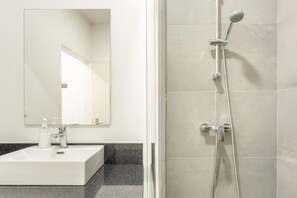 Een badkamer met een witte wastafel, spiegel en douche.