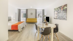 Une chambre d’hôtel comprenant un lit, un canapé, une table à manger avec des chaises, un téléviseur et des œuvres d’art accrochées au mur.