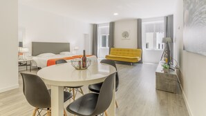 Une chambre d’hôtel moderne comprenant un lit, une table à manger avec des chaises, un canapé et une grande fenêtre.