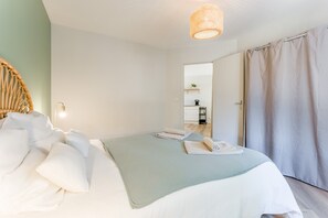 Une chambre à coucher avec un lit, une lampe de chevet, une porte et une vue sur une autre pièce.