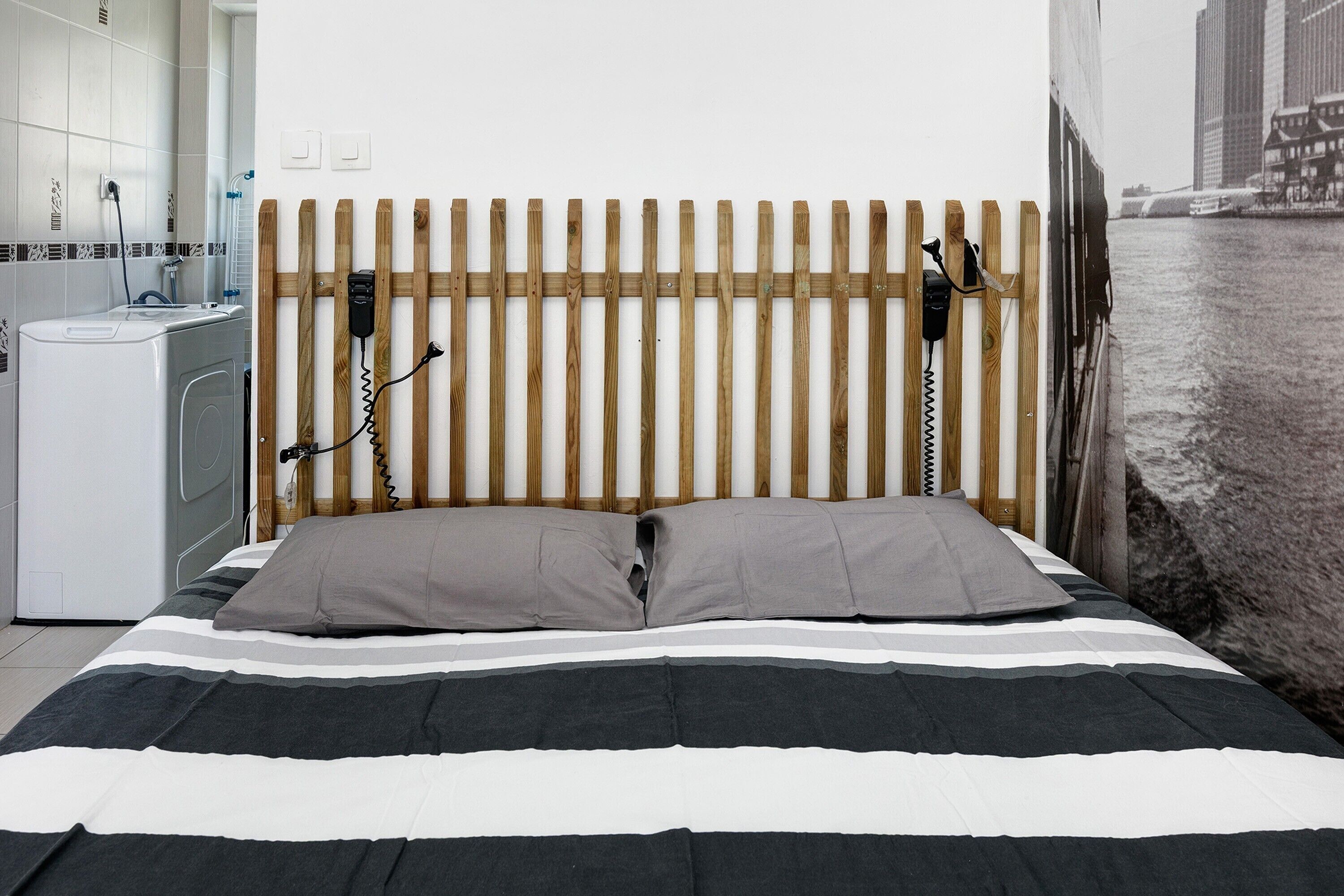 A bed with a striped bedspread, a wooden headboard, and a view of a river.