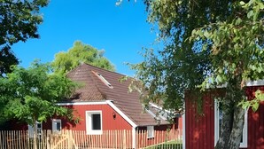 A red building with a sloped roof, a wooden fence, and a stone bench.