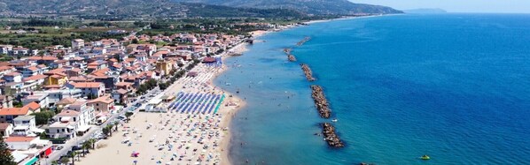 Une ville côtière dotée d’une plage, de bâtiments et d’une digue rocheuse.