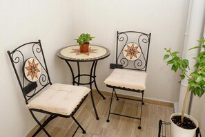 Two black metal chairs with cushioned seats and backs, a small round table with a potted plant, and a white wall. - Apartment 'Polisher' with Shared Terrace, Wi-Fi and Air Conditioning (Heraklion)