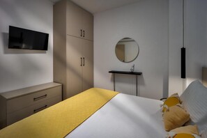 A bedroom with a bed, a TV mounted on the wall, a mirror, and a bedside table. - Apartment 'Polisher' with Shared Terrace, Wi-Fi and Air Conditioning (Heraklion)