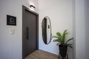 A hallway with a door, a wall-mounted mirror, a potted plant, and a sign labeled 'Ceramicist.' - Apartment 'Polisher' with Shared Terrace, Wi-Fi and Air Conditioning (Heraklion)