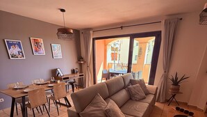 Ein Wohnzimmer mit einer Couch, einem Esstisch, Stühlen und einem kleinen Couchtisch.
