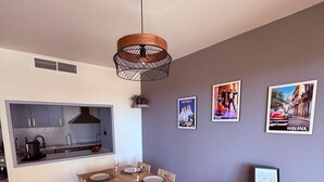 Ein Essbereich mit einem für vier Personen gedeckten Tisch, eine Küche mit modernen Geräten und Wandkunst, die Spanien und Havanna zeigt.