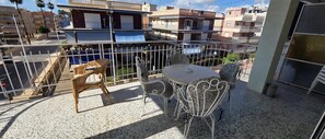 Ein Balkon mit Tisch und Stühlen, einem weißen Geländer und Blick auf benachbarte Gebäude.