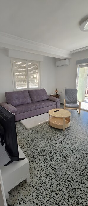 A living room with a sofa, a coffee table, a TV, and a chair.