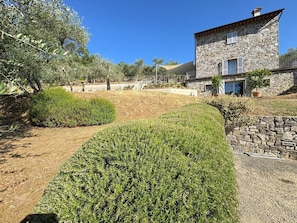 A stone building with a balcony, surrounded by well-maintained hedges and olive trees. - Villa 'La Grecale - Lucca' with Private Pool, Wi-Fi, and Air Conditioning (Capannori)