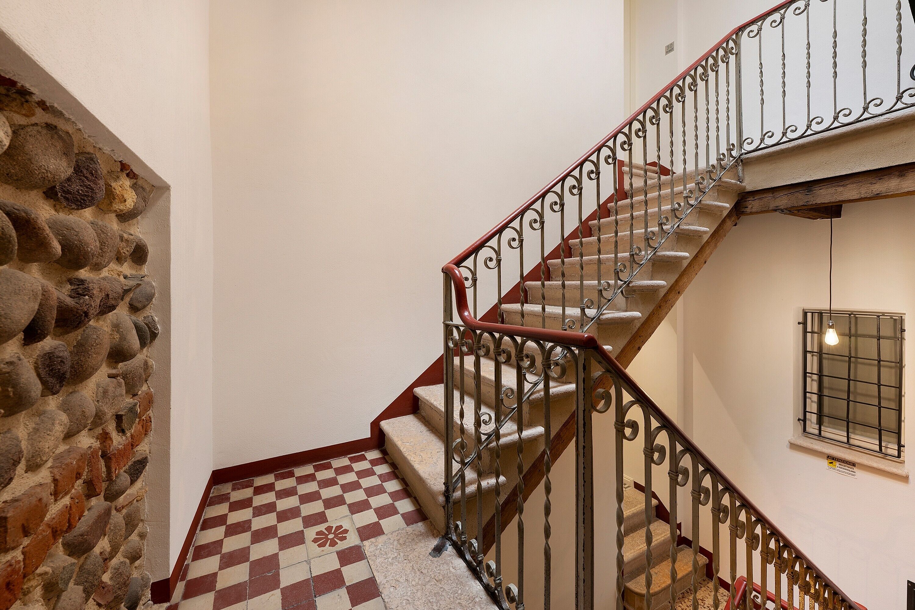 A staircase with a stone wall on one side and a checkered floor.