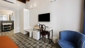A modern room with a white desk, a blue chair, a flat-screen TV, and a patterned floor. - Room 'Stanza S20' with Wi-Fi and Air Conditioning (Verona)