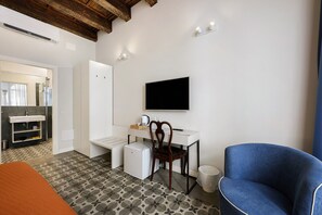 Ein modernes Zimmer mit weißem Schreibtisch, blauem Stuhl, Flachbildfernseher und einem gemusterten Boden.