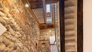 A stone-walled corridor with a wooden staircase and a fire extinguisher. - Room 'Stanza S20' with Wi-Fi and Air Conditioning (Verona)