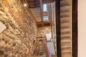 Ein Korridor mit Steinwänden, einer Holztreppe und einem Feuerlöscher.