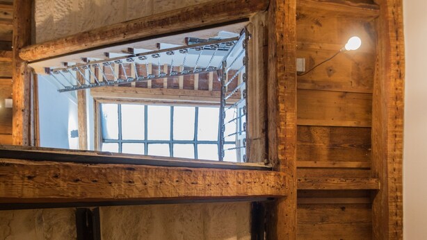 A rustic room with stone flooring, wooden walls, and a window with a metal rack. - Room 'Stanza S20' with Wi-Fi and Air Conditioning (Verona)