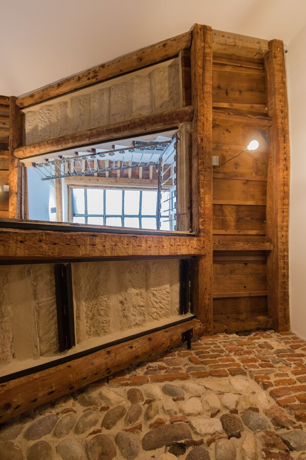 Ein rustikaler Raum mit Steinböden, Holzwänden und einem Fenster mit einem Metallgestell.