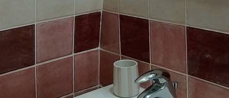 A bathroom with a white sink, a mirror, and red and white tiles.