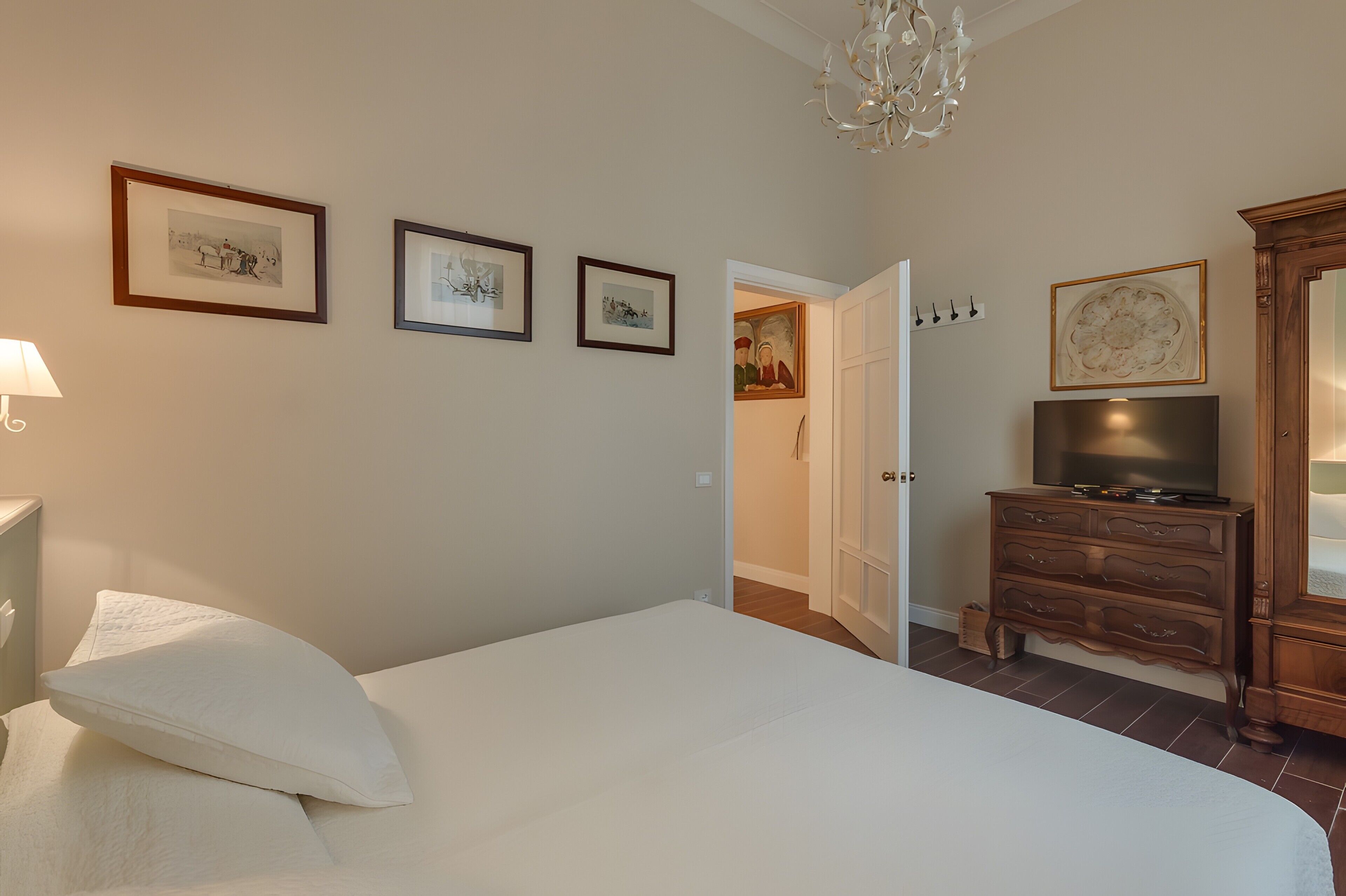 Quarto com cama, penteadeira, televisão e quadros na parede.