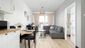 Un soggiorno moderno con zona pranzo, un divano grigio e una TV su un mobile in legno.