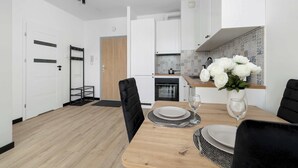 Una cucina moderna con mobili bianchi, un piano di lavoro in legno e un'area pranzo con tavolo apparecchiato per due persone.
