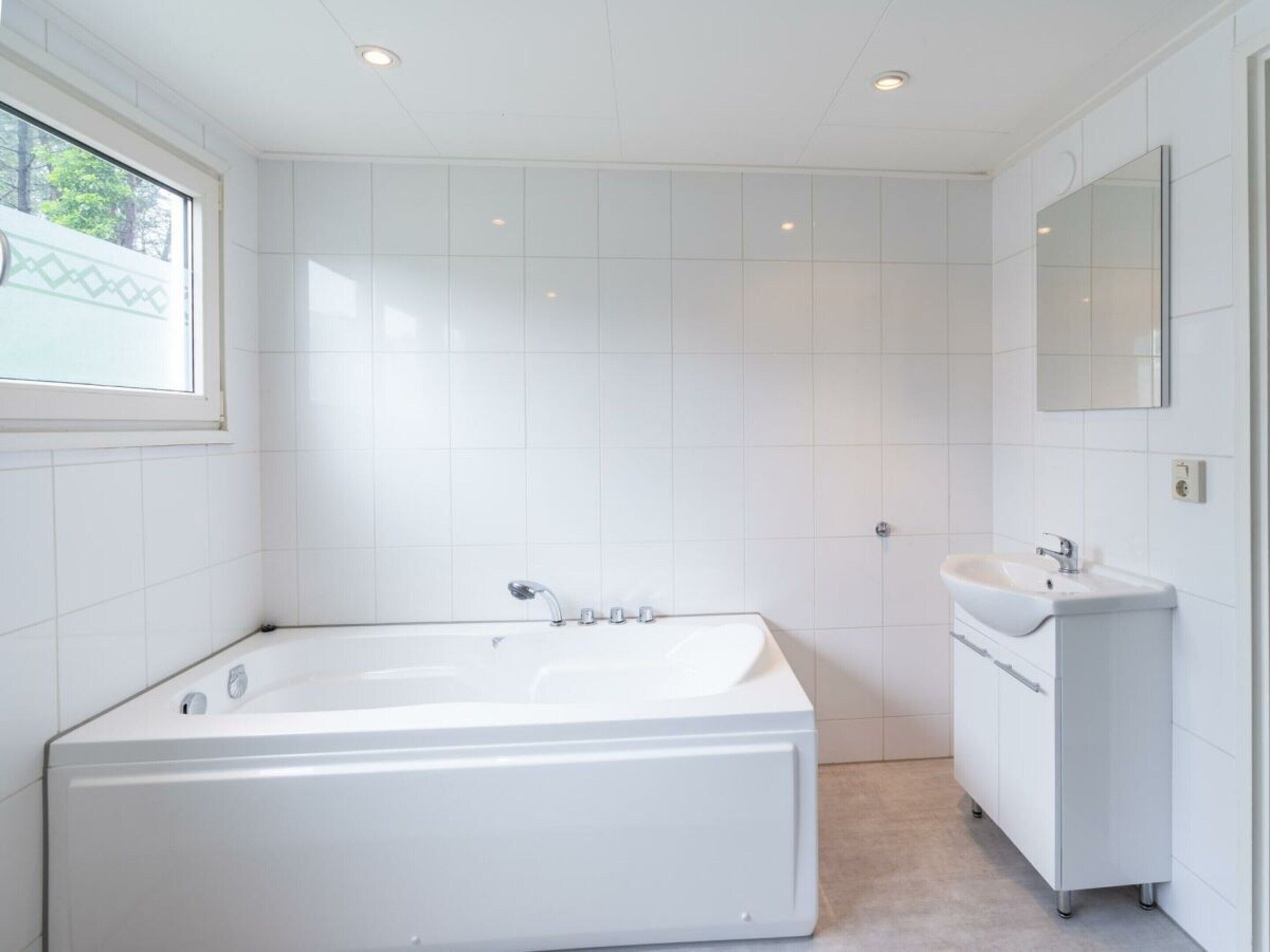 A modern bathroom with a large bathtub, a sink, and a mirror. - Hackfort L"etage 10 (Brunssum)