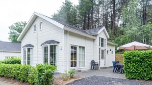 A white two-story house with a covered patio, gravel driveway, and a hedge. - Hackfort L"etage 10 (Brunssum)