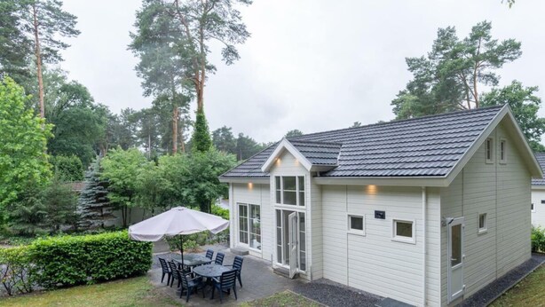 A single-story house with a patio, a table with chairs, and an umbrella. - Hackfort L"etage 10 (Brunssum)
