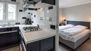 A modern kitchen with a central island, a built-in stove, and a coffee machine. - Hackfort L"etage 10 (Brunssum)