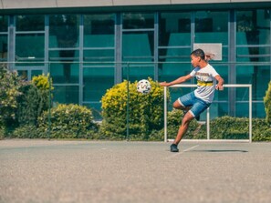 A person playing soccer on an outdoor court with a modern building in the background. - Holiday Home in Dordrecht With Terrace (Dordrecht)