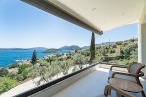 Ein Balkon mit Meerblick, einem Stuhl und einer Glastrennwand.