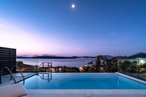 Ein Pool mit Blick auf das Meer und die Berge im Abenddämmerung.