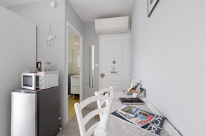 Una cocina compacta con microondas, refrigerador y comedor con mesa y sillas.