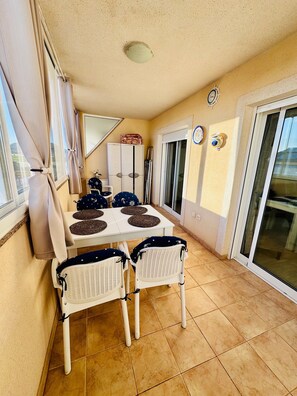 A dining area with a table and chairs, a sliding glass door, and a ceiling light. - Apartment 'Casa Sol Mar Menor' with Shared Pool, Balcony and Wi-Fi (Los Nietos)