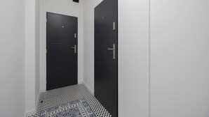 A narrow hallway with a black door on the right and a black door on the left. - A Functional Studio in the City Centre | Stary Browar (Poznań)