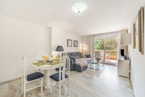 Ein modernes Wohnzimmer mit Essbereich, einer Couch, einem Fernseher und einem Balkon mit Blick.