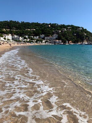 Una spiaggia con acque cristalline, una riva sabbiosa e edifici sullo sfondo.