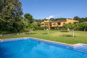 A swimming pool with a tiled edge, surrounded by a well-maintained lawn and trees. - Villa 'Pastora' with Sea Views, Wi-Fi, and Air Conditioning (Llafranc)
