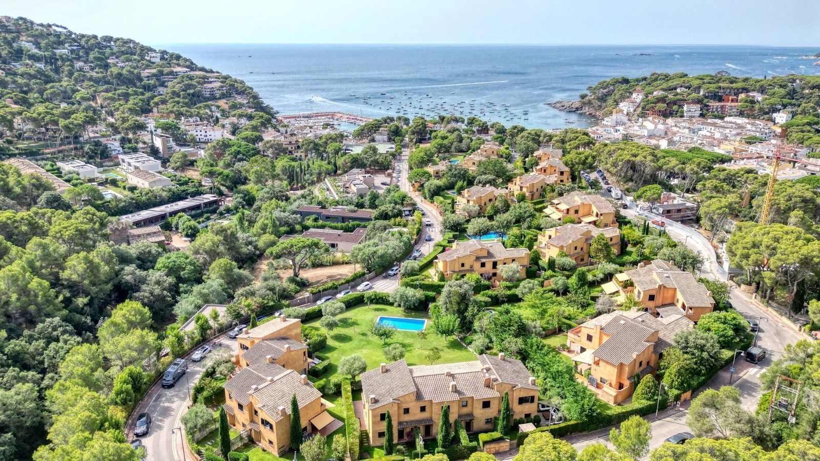 Un quartier résidentiel avec des maisons, une piscine et une vue sur la mer.