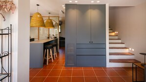 A modern kitchen with a central island, pendant lights, and a staircase leading to an upper level.