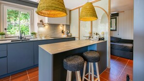 A modern kitchen with a central island, two woven pendant lights, and a large window.