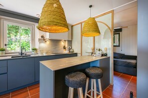 A modern kitchen with a central island, two woven pendant lights, and a large window. - Villa 'Pastora' with Sea Views, Wi-Fi, and Air Conditioning (Llafranc)
