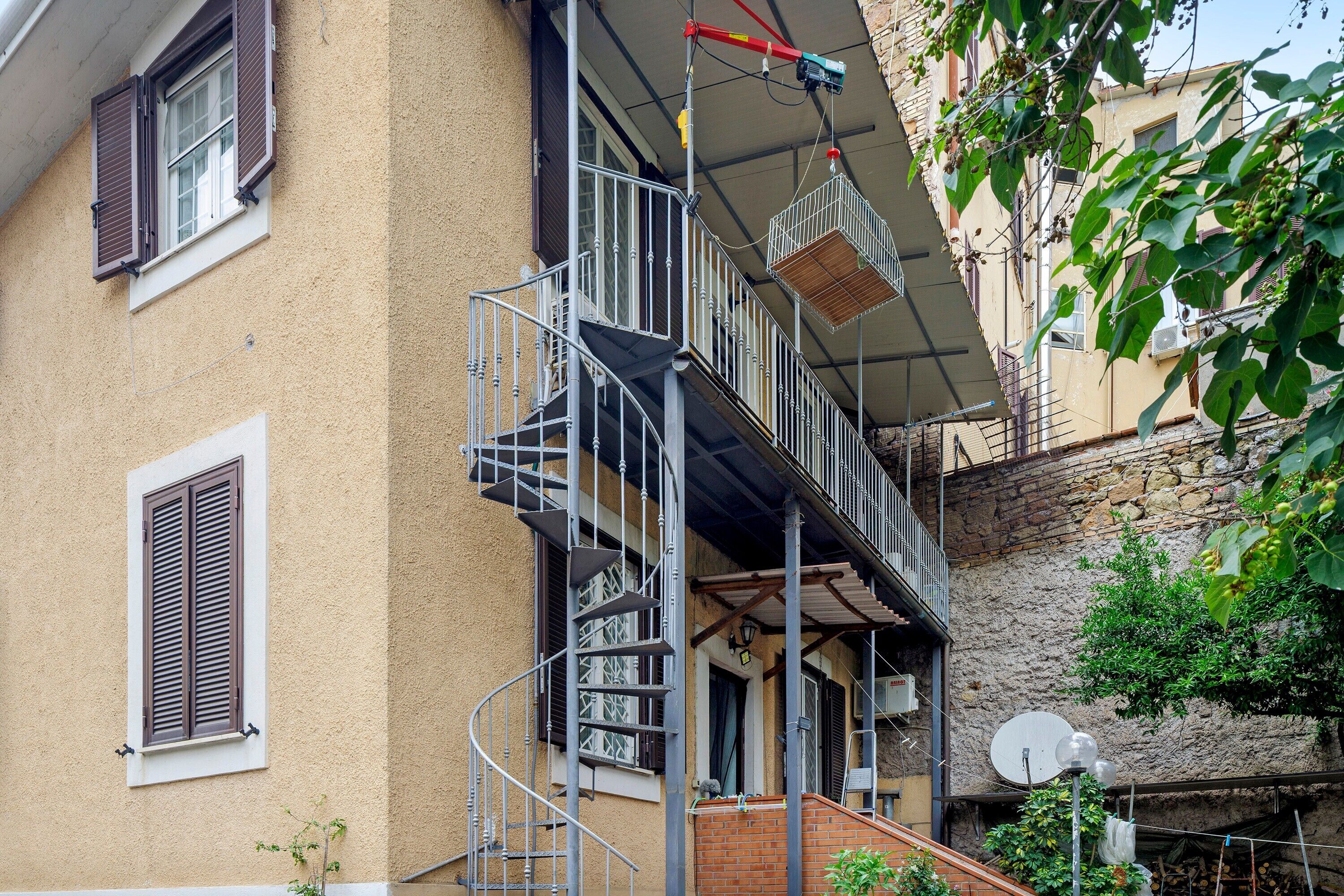 Un edificio a più piani con una scala a chiocciola, un balcone e un'antenna parabolica.