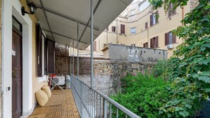 A balcony with a metal railing, a welcome mat, and a door with a brown shutter. - Apartment 'Portatrastevere' with Balcony, Wi-Fi and Air Conditioning (Rome)