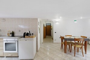 Cozinha com fogão, geladeira e mesa de jantar com cadeiras.