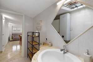 Ein modernes Badezimmer mit einem großen Waschbecken, einem Spiegel und einem Oberlicht.