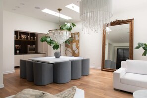 Un salon moderne avec un coin repas, un lustre et un grand miroir.