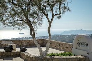 Eine Steinmauer mit einem Baum, einem Schild mit der Aufschrift 'Zatrikion Private Area' und einem Schild für 'Zatrikion Santorini Villa'.