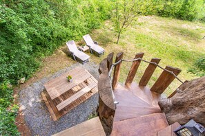 Un escalier en bois mĂšne Ă une terrasse amĂ©nagĂ©e avec des siĂšges et une table pour lâextĂ©rieur.